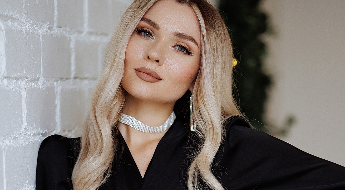 Woman with long hair posing against a wall.